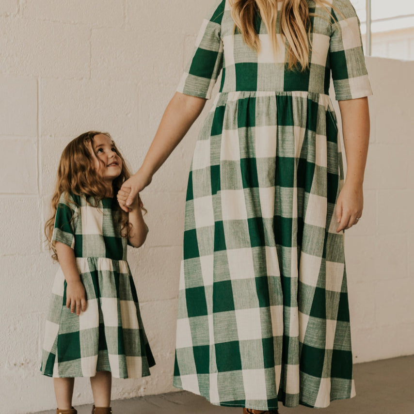 Now you and your mini can match in this ROOLEE classic! This dress features a timeless buffalo plaid that is bold, sophisticated and the perfect style for every occasion. Breathable, woven material is paired with hip pockets, half sleeves, a full lining, a gathered waist, and a flowing skirt. The Mini Maddie Buffalo Plaid Dress is adorable, versatile, and sure to be your daughter's favorite dress! Green Plaid
