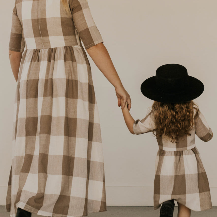 Now you and your mini can match in this ROOLEE classic! This dress features a timeless buffalo plaid that is bold, sophisticated and the perfect style for every occasion. Breathable, woven material is paired with hip pockets, half sleeves, a full lining, a gathered waist, and a flowing skirt. The Mini Maddie Buffalo Plaid Dress is adorable, versatile, and sure to be your daughter's favorite dress! Tan Plaid 