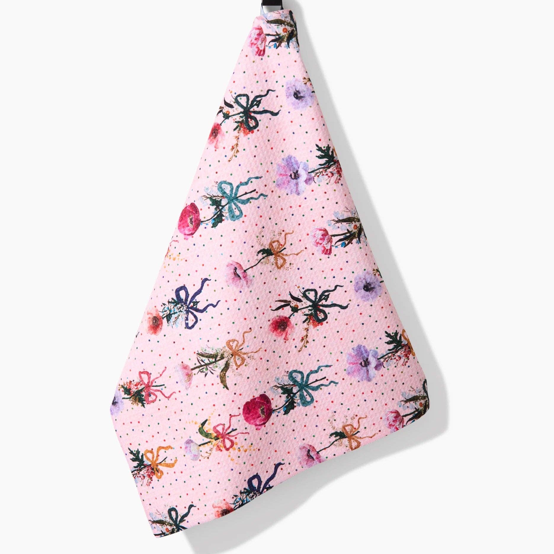 Pink towel with floral and bow pattern hanging on a white background Tea Towel
