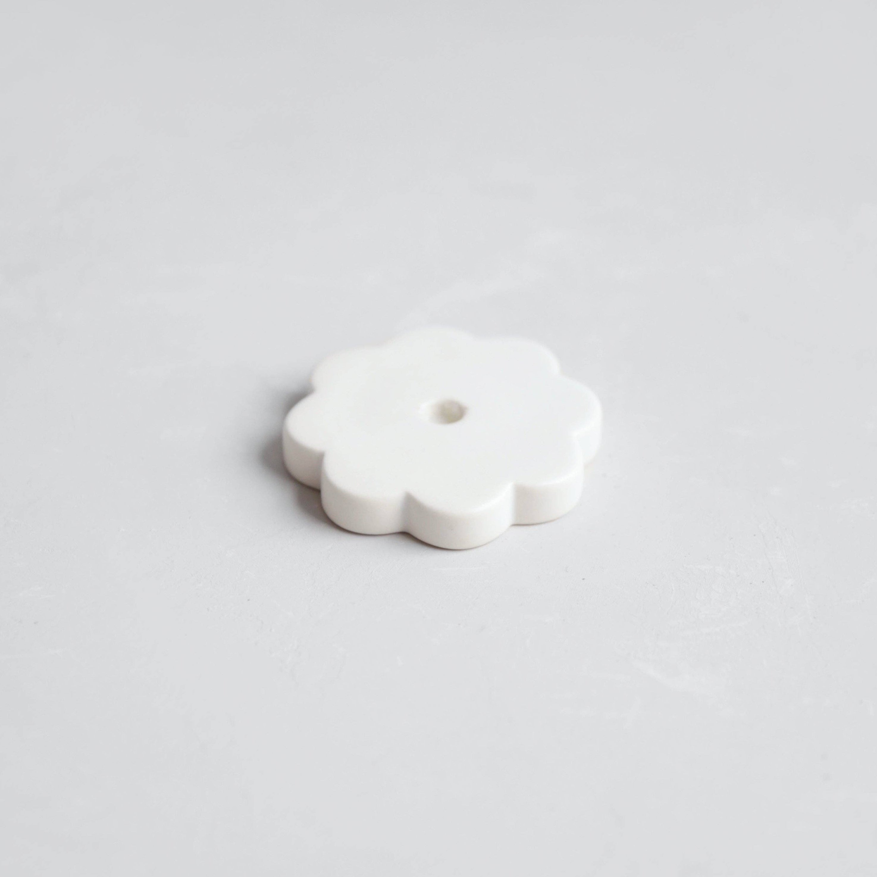 White ceramic flower-shaped object on a light gray background