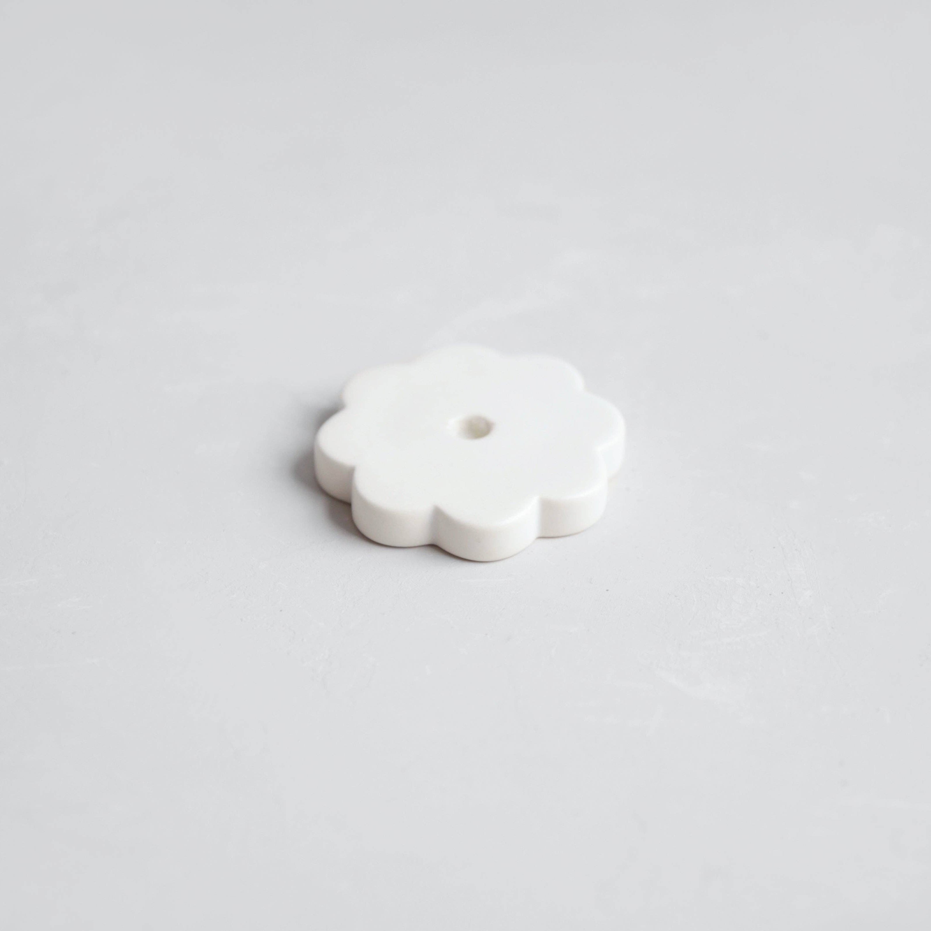 White ceramic flower-shaped object on a light gray background