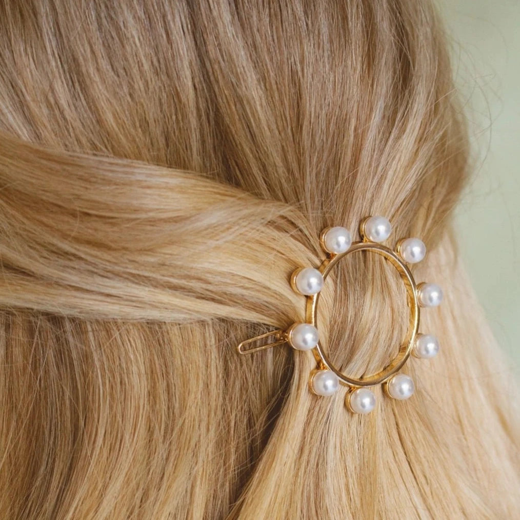 Add a touch of luxury to any hairstyle with Cleo Clip. This gold circle adorned with pearls serves as both a hair clip and an elegant accessory. Stay classy in style.