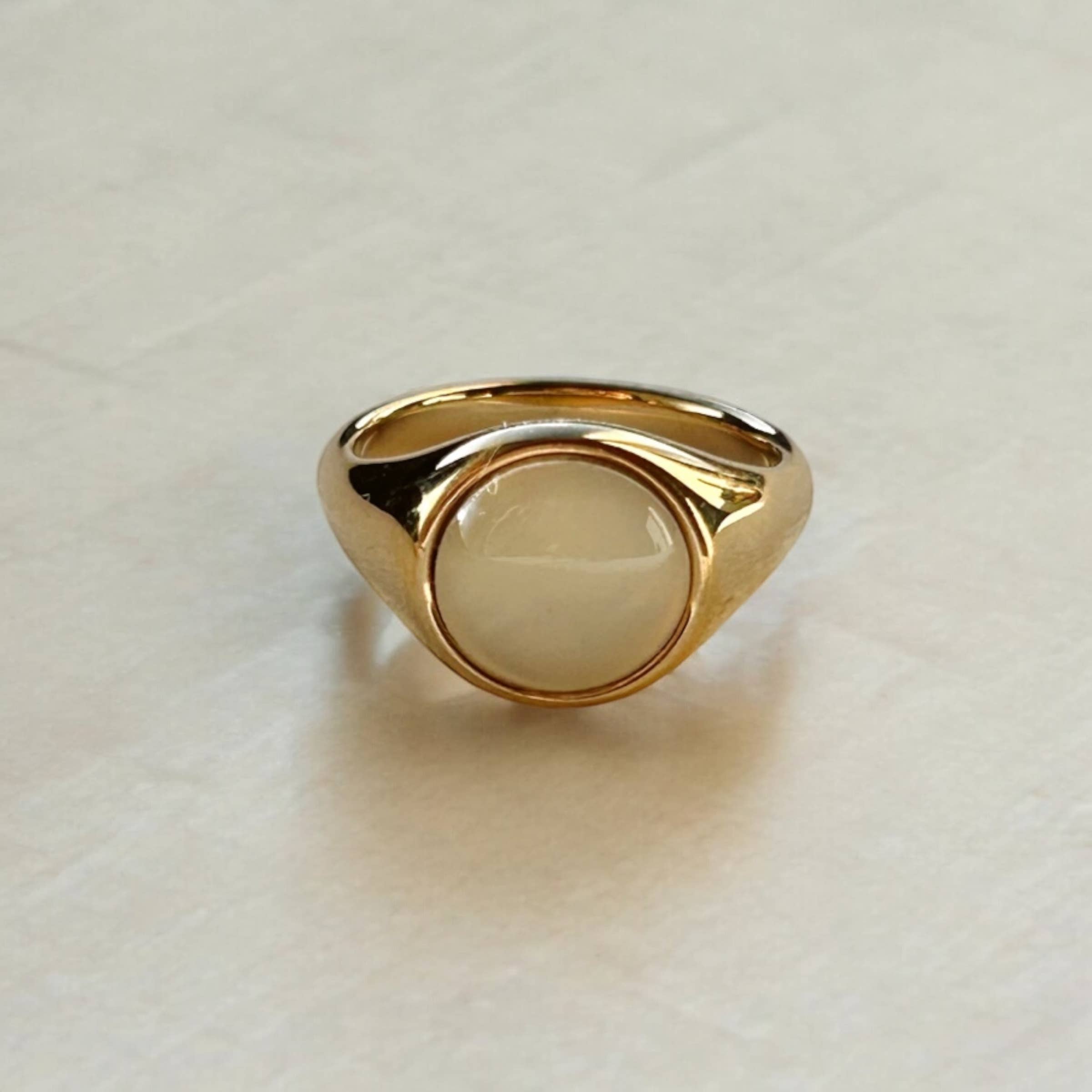 Gold ring with a beige stone on a light background