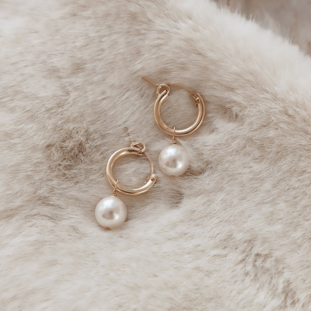 Add a touch of elegance with our Audrey Pearl Hoop Earrings. These stylish hoops feature delicate pearls for a classy yet playful look. Perfect for any occasion, these earrings are sure to add a touch of charm to any outfit. 