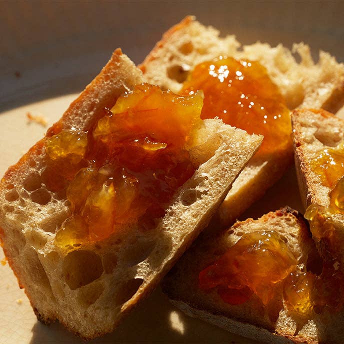 Slices of bread with orange jam on a wooden surface