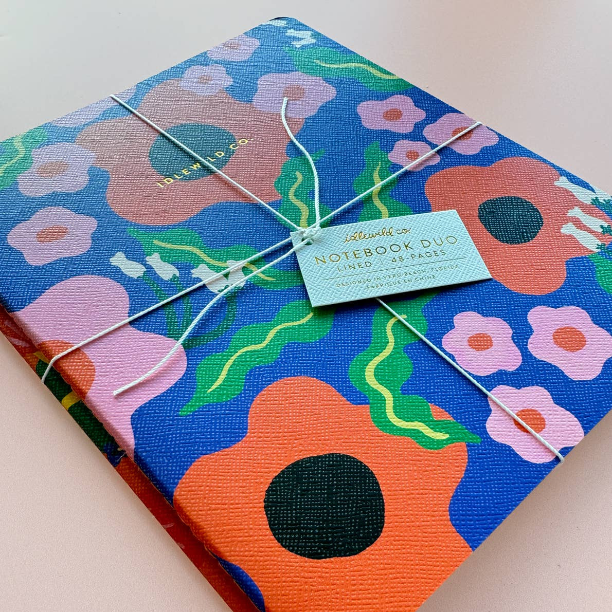 Floral notebook with a tag on a light pink background