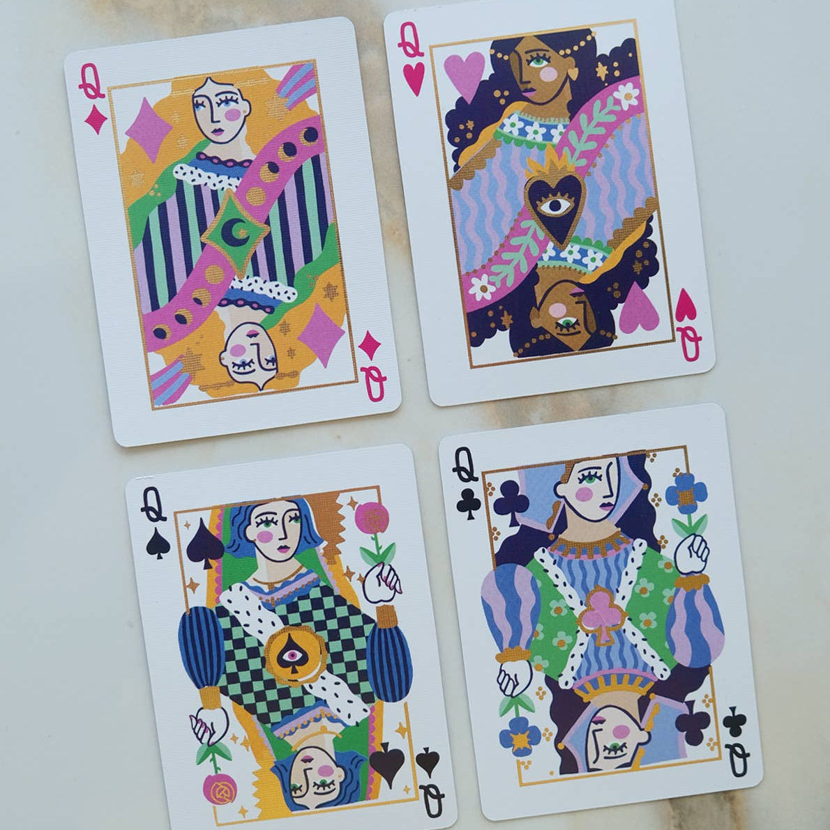 Four playing cards with colorful designs on a textured surface