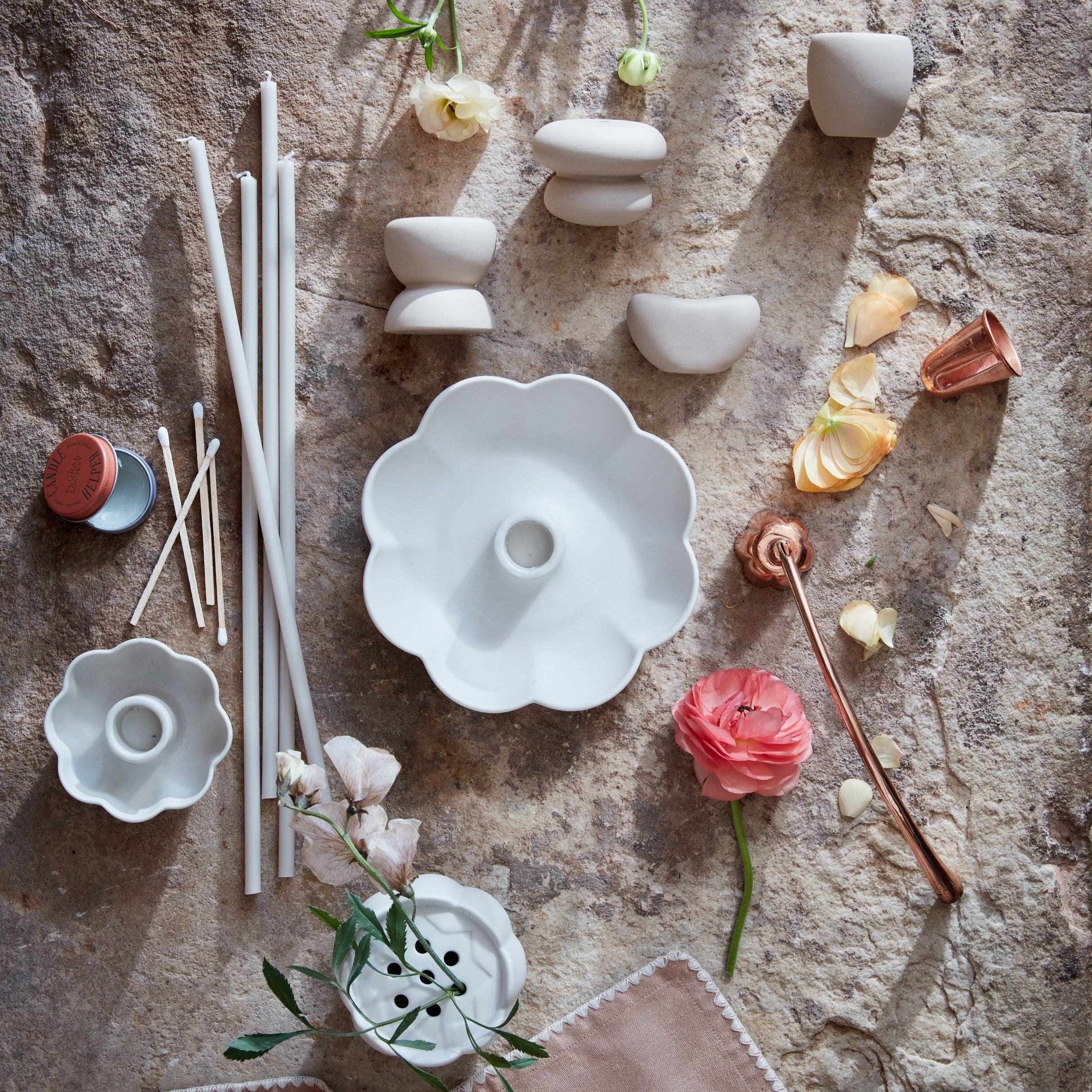 Collection of white ceramic items and flowers on a textured surface