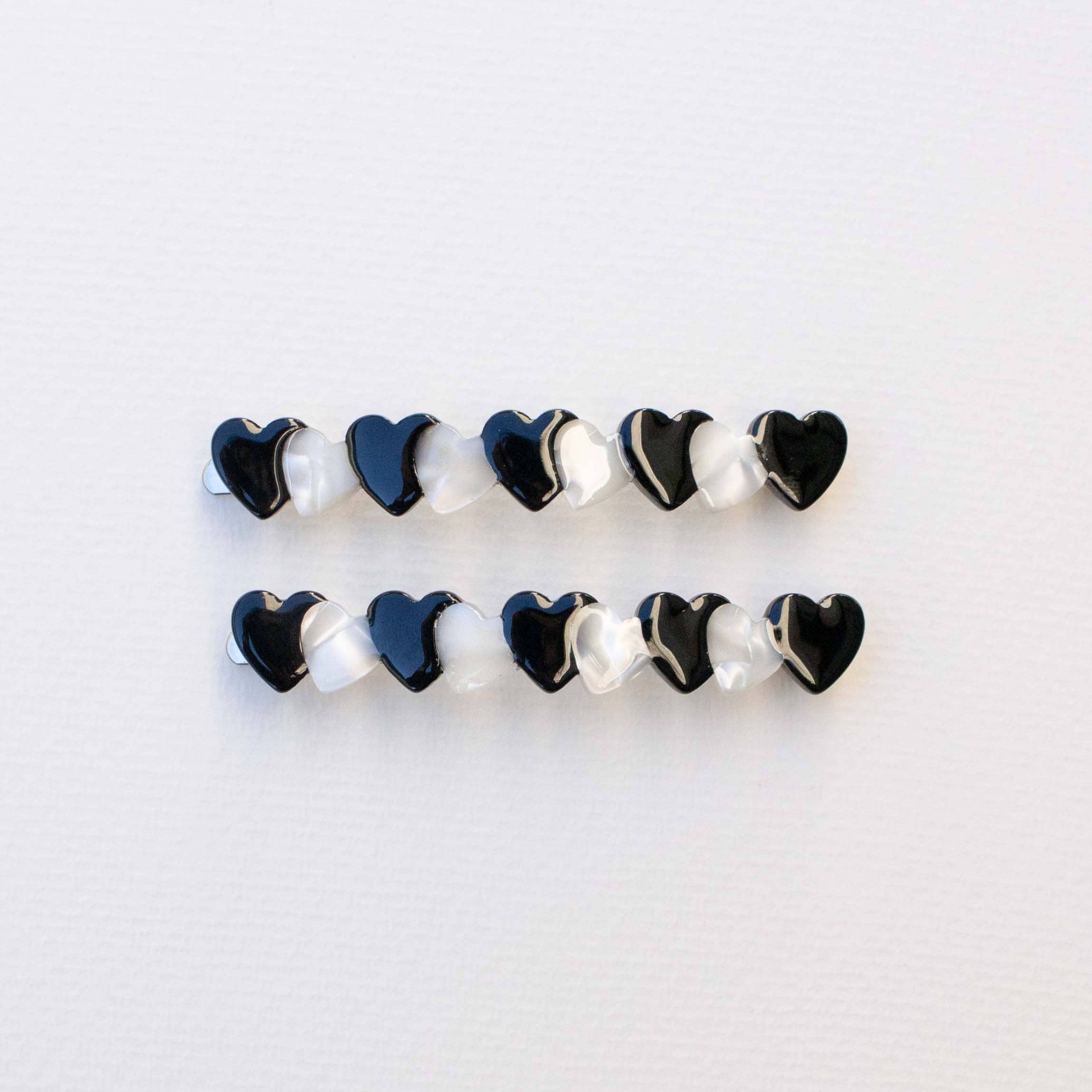 Hold onto your style with this charming hair pin set of two. Each sleek black pin is adorned with delicate hearts running along its length, adding a sweet romantic touch to any hairstyle. Whether you're securing an updo, creating texture, or simply keeping strands in place throughout the day, these pins blend functionality with understated elegance. Perfect for everyday wear or special occasions, this set gives you versatile styling options while celebrating those little details that make you smile.