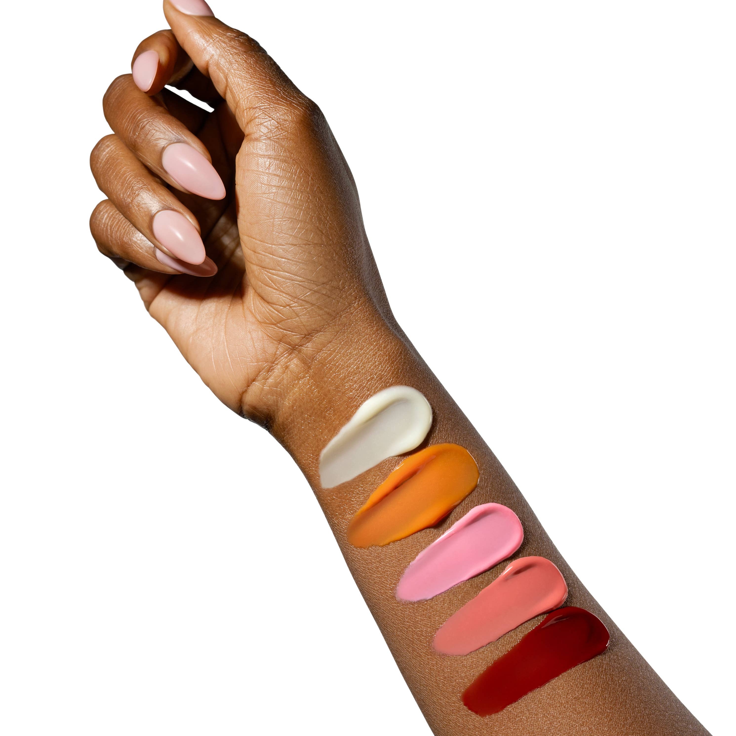 Hand with swatches of different lip colors on a white background