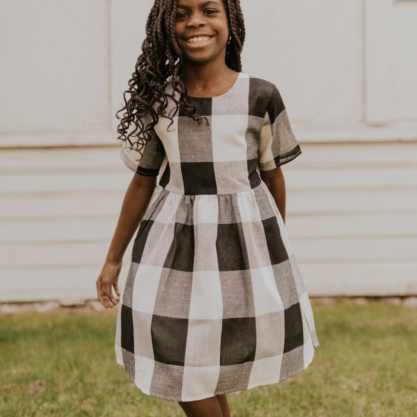 Now you and your mini can match in this ROOLEE classic! This dress features a timeless buffalo plaid that is bold, sophisticated and the perfect style for every occasion. Breathable, woven material is paired with hip pockets, half sleeves, a full lining, a gathered waist, and a flowing skirt. The Mini Maddie Buffalo Plaid Dress is adorable, versatile, and sure to be your daughter's favorite dress! Black Plaid