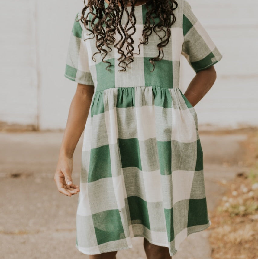 Now you and your mini can match in this ROOLEE classic! This dress features a timeless buffalo plaid that is bold, sophisticated and the perfect style for every occasion. Breathable, woven material is paired with hip pockets, half sleeves, a full lining, a gathered waist, and a flowing skirt. The Mini Maddie Buffalo Plaid Dress is adorable, versatile, and sure to be your daughter's favorite dress! Green Plaid
