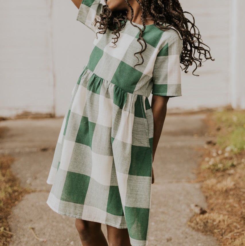 Now you and your mini can match in this ROOLEE classic! This dress features a timeless buffalo plaid that is bold, sophisticated and the perfect style for every occasion. Breathable, woven material is paired with hip pockets, half sleeves, a full lining, a gathered waist, and a flowing skirt. The Mini Maddie Buffalo Plaid Dress is adorable, versatile, and sure to be your daughter's favorite dress! Green Plaid