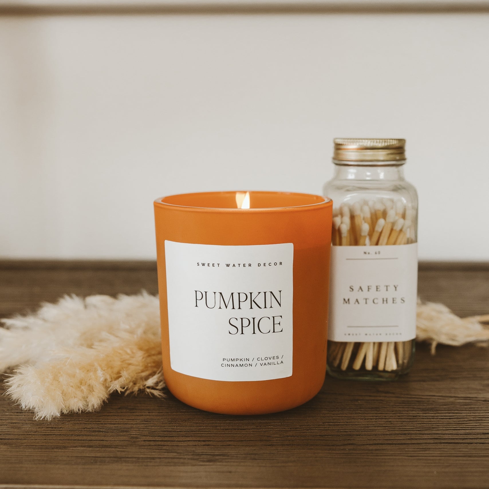 Pumpkin spice candle with matches on a wooden surface