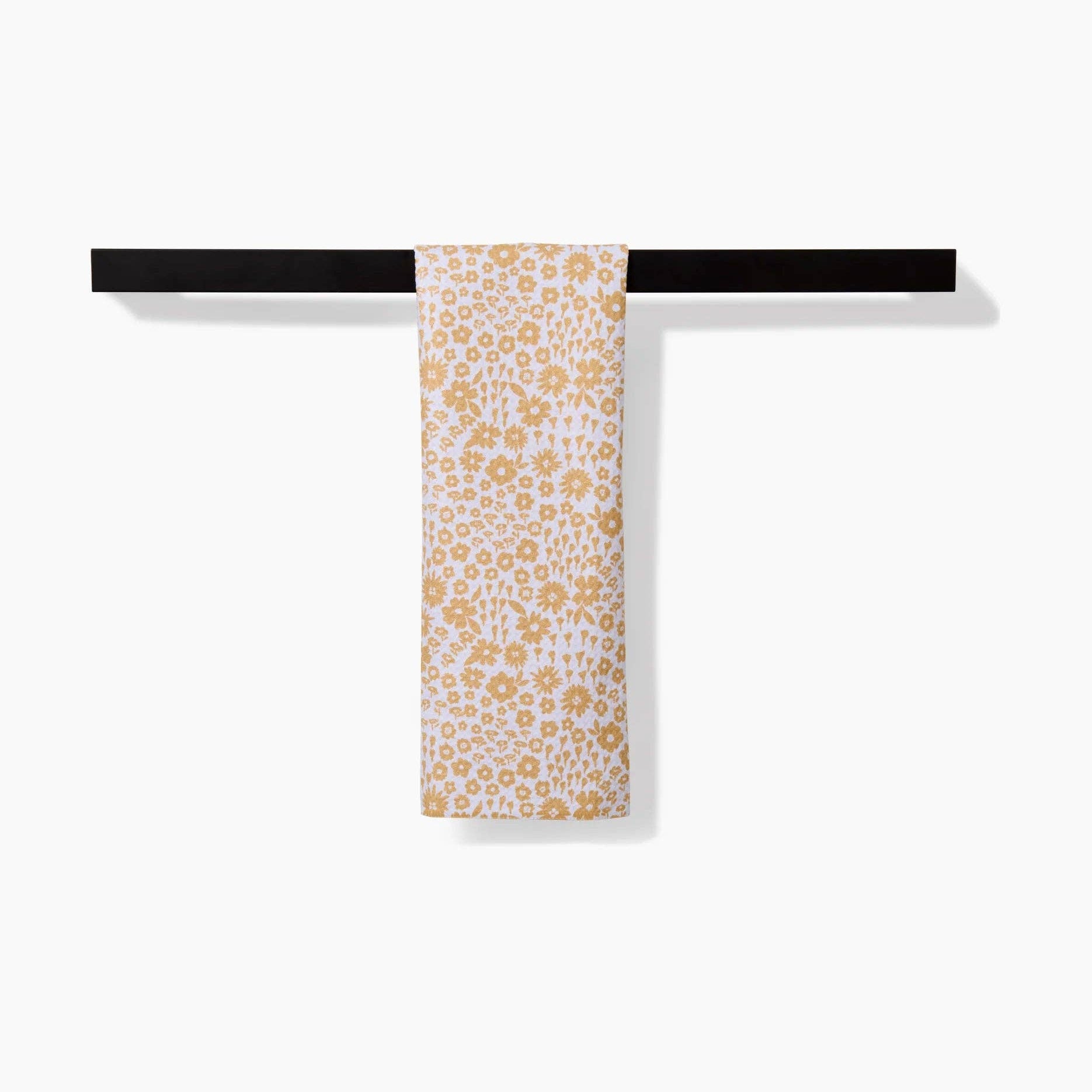 Towel with yellow floral pattern hanging on a black towel rack against a white background Tea Towel