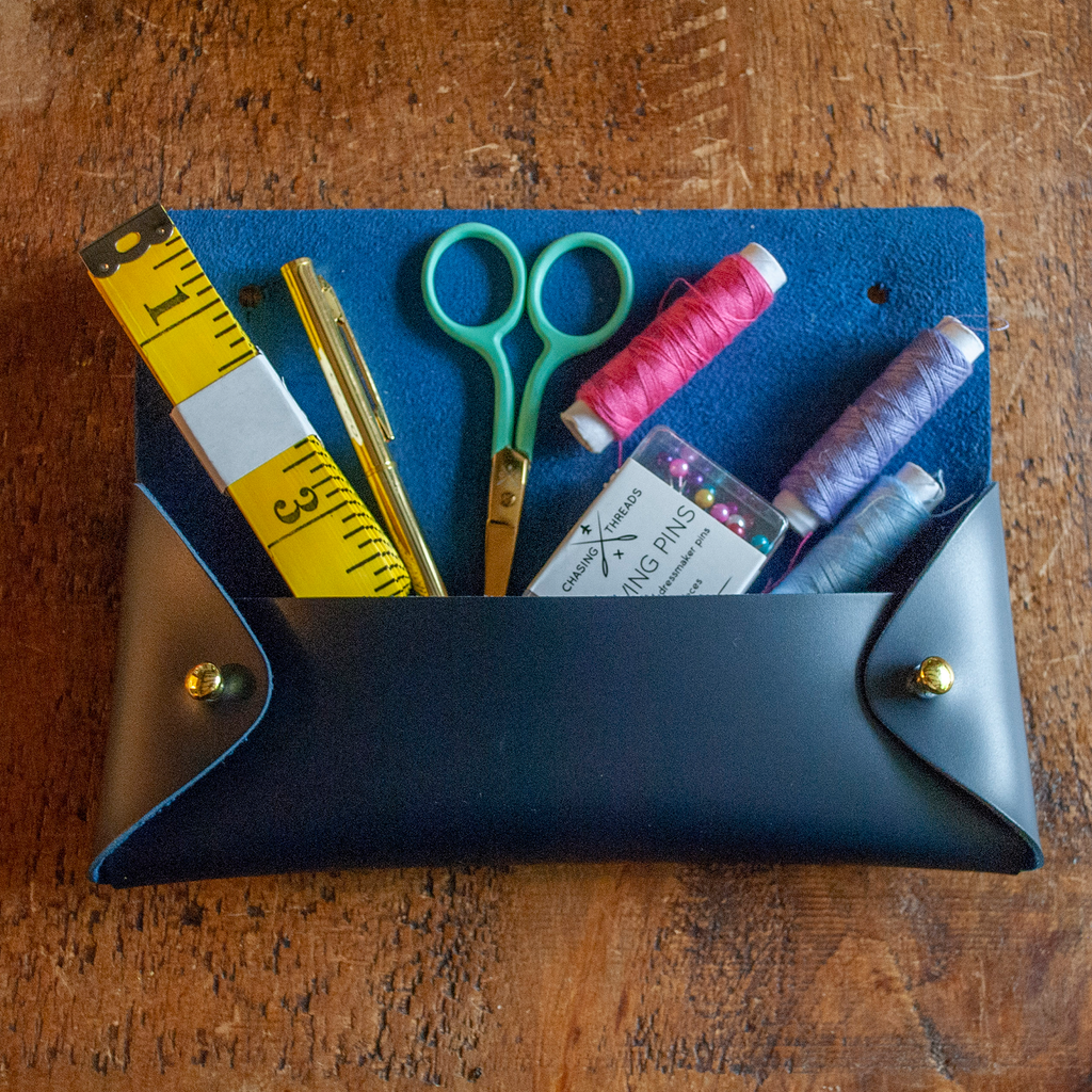 Stitch your own way - this envelope pocket is ideal as a pencil or glasses case and allows you to sew any unique design. Whether you stitch initials, a slogan or the sunglasses template included, it opens out fully for easy stitching. It also opens 2 ways, so it can open from the side or from the top - just pop the metal buttons to fold up whichever way you prefer. The Navy pouch comes with teal & gold thread &amp; needle wrapped on our pen thread-board. It includes our 3D alphabet template to add initials