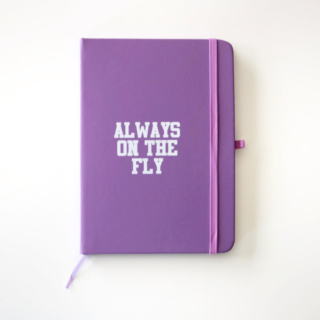 purple hardcover journal reading "Always on the fly" in a white font