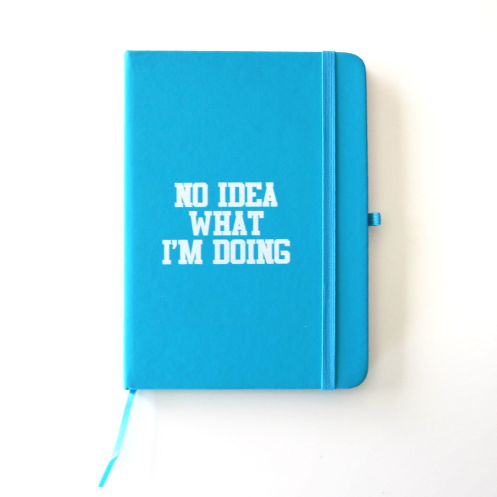 blue hardcover notebook reading "No idea what I'm doing" in a white font