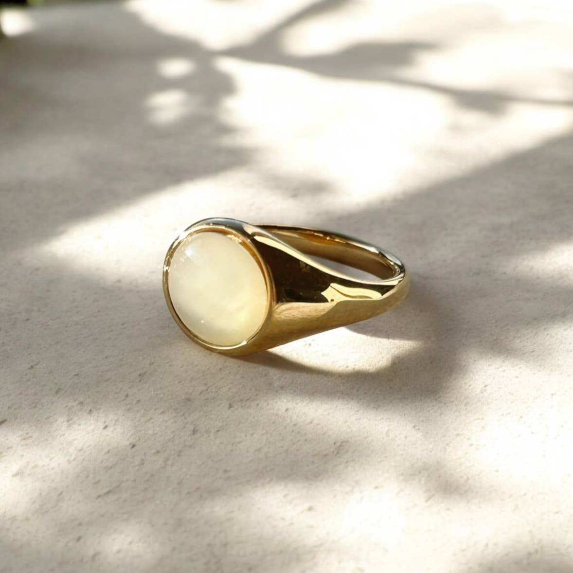 Gold ring with a white stone on a light surface