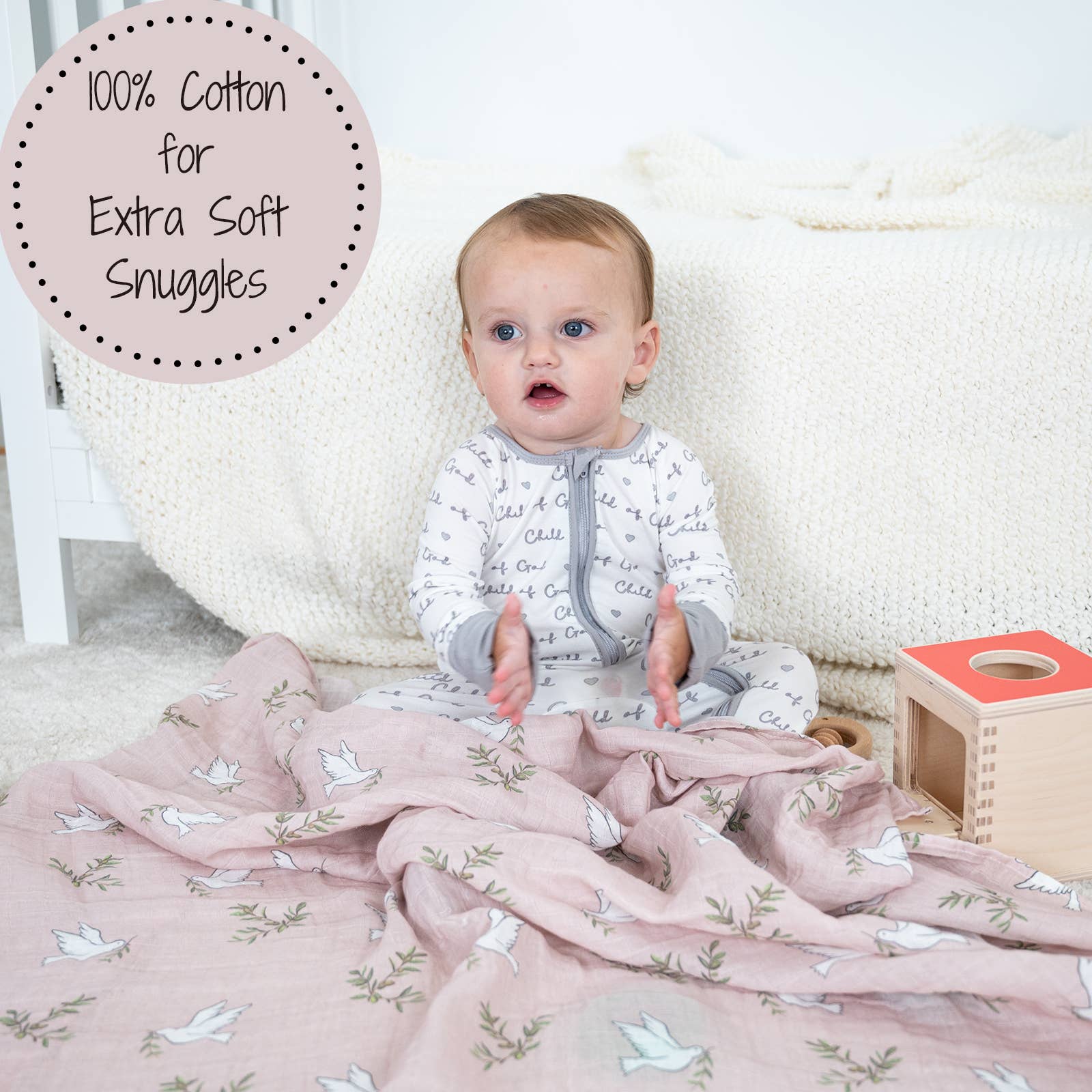 Baby sitting on a pink blanket with text about 100% cotton