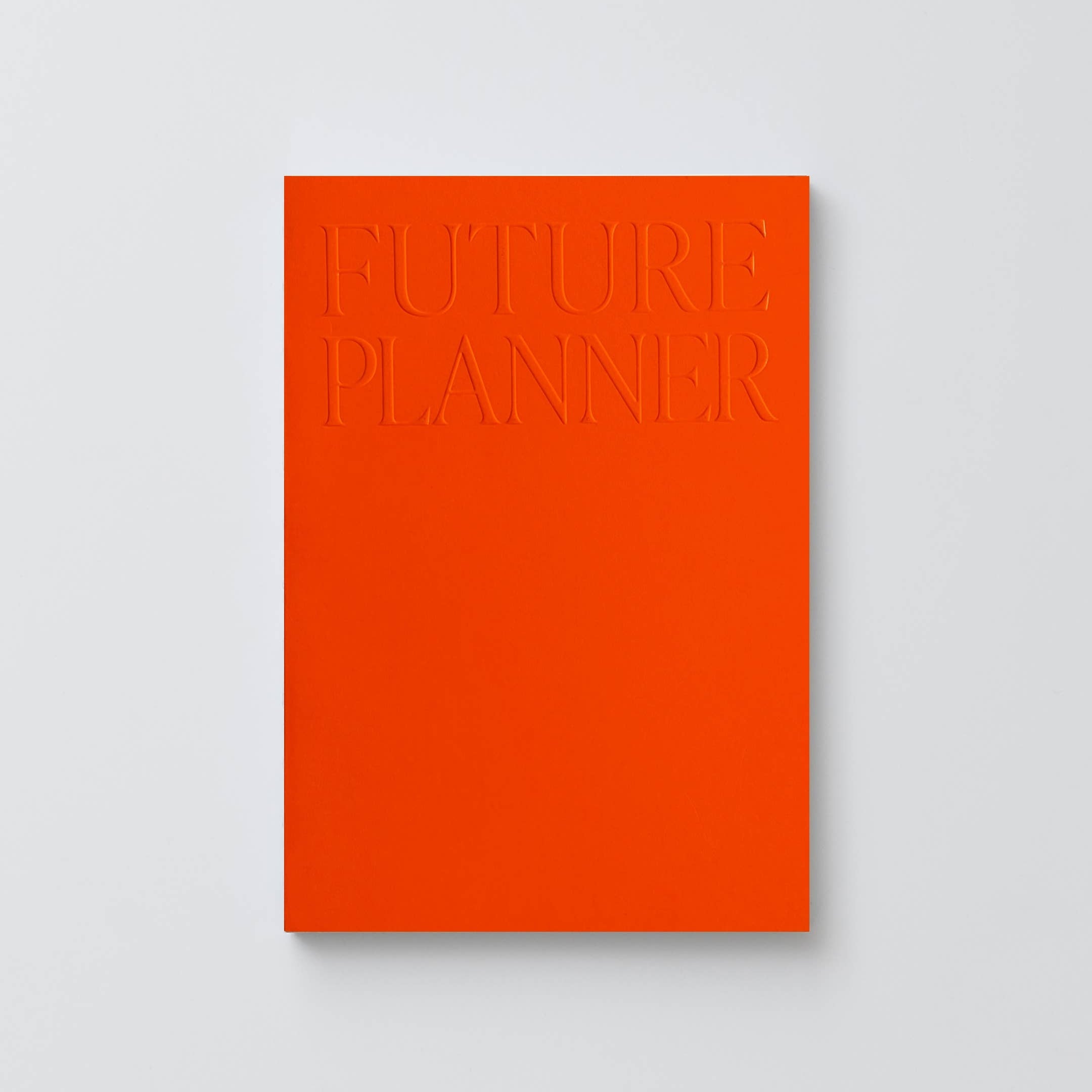 A minimalist orange hardcover journal titled 'FUTURE PLANNER' with embossed lettering, shown against a light gray background.