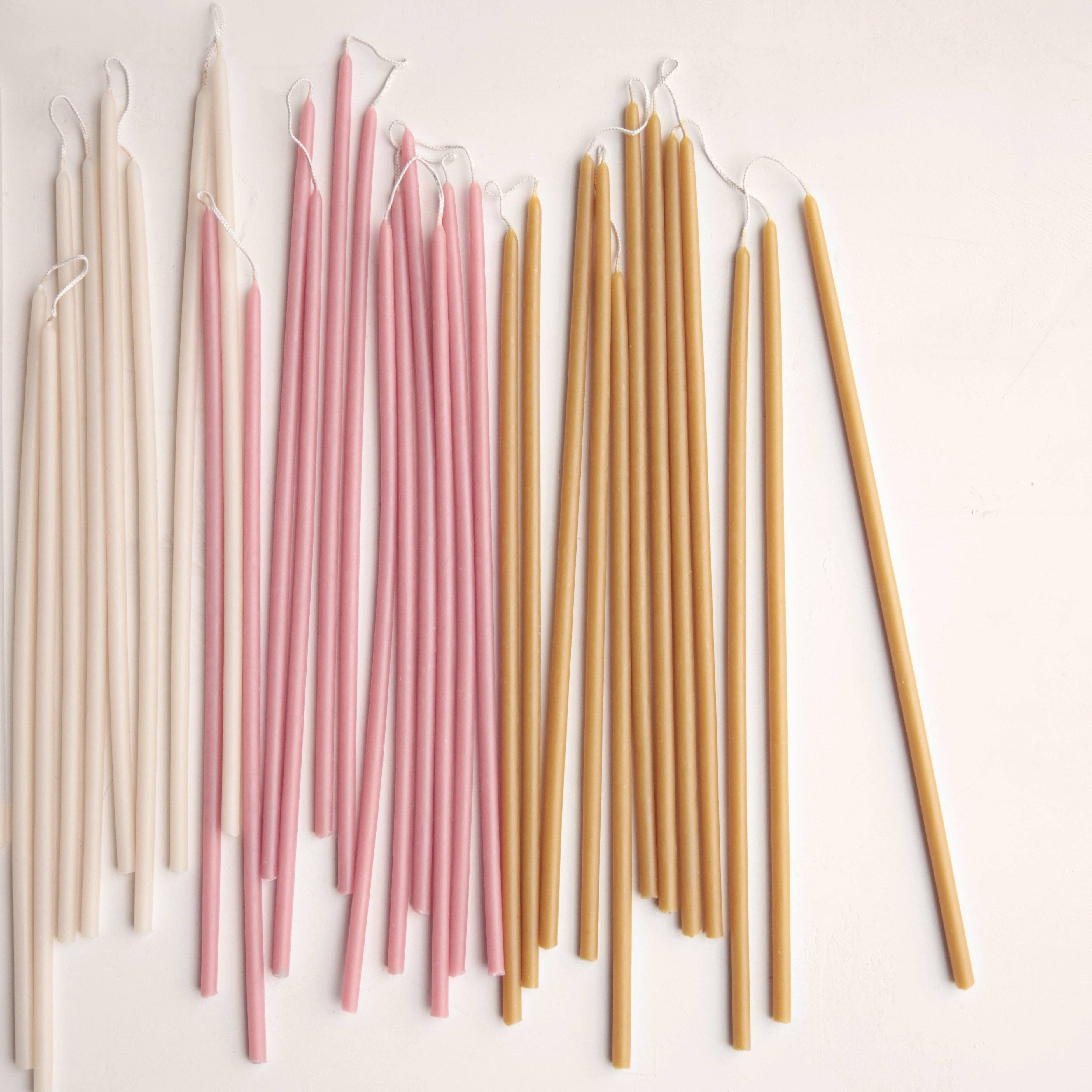 Set of candles in various colors including beige, pink, and brown on a light background