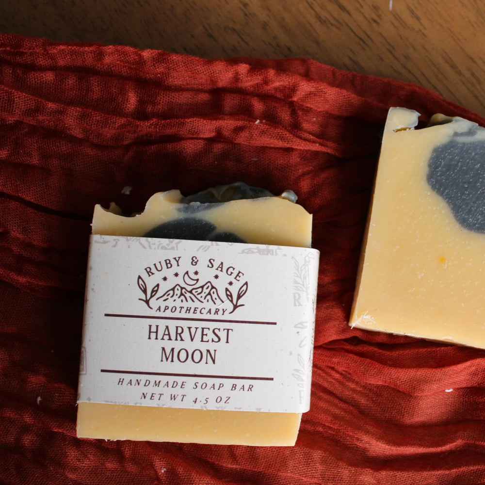 Pale orange soap with charcoal swirls. Pictured against a rust colored table runner.
