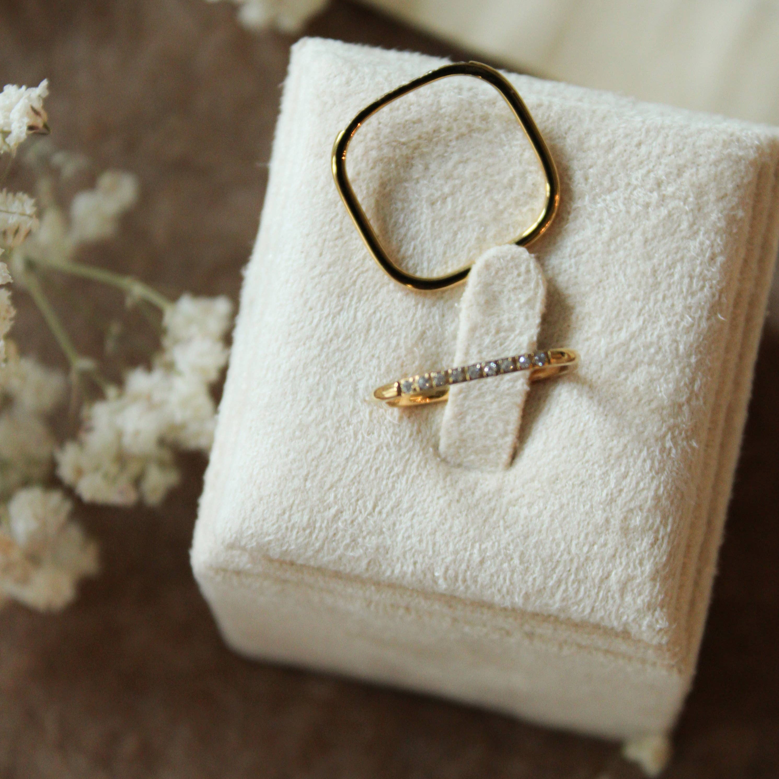 Jewelry box with rings on a textured surface with white flowers.