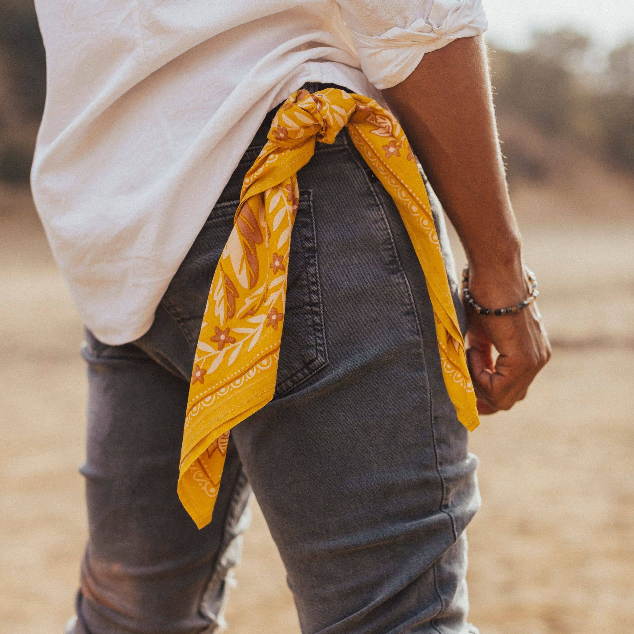 Person wearing a white shirt and yellow scarf with a blurred natural background