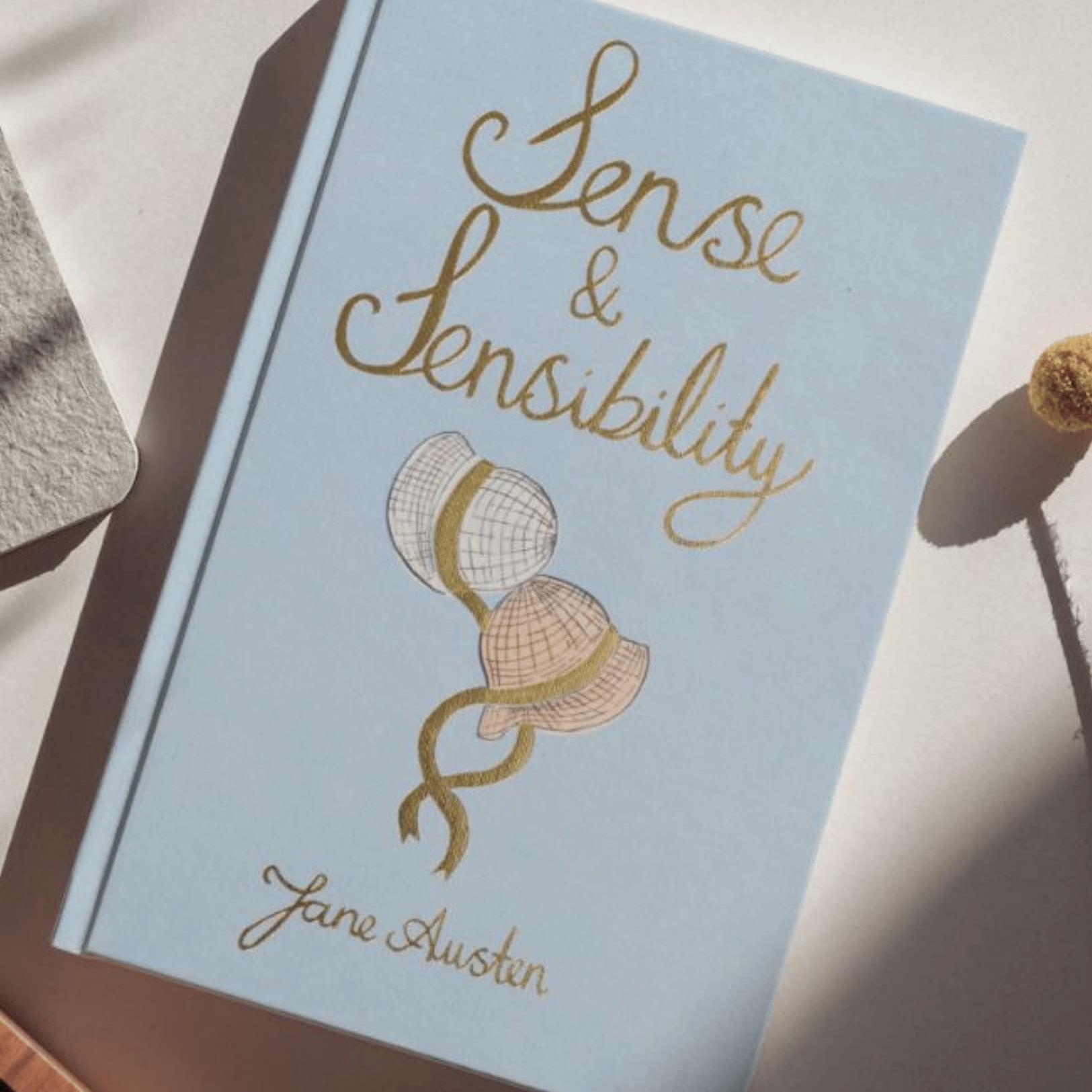 Book titled 'Sense & Sensibility' by Jane Austen on a light surface