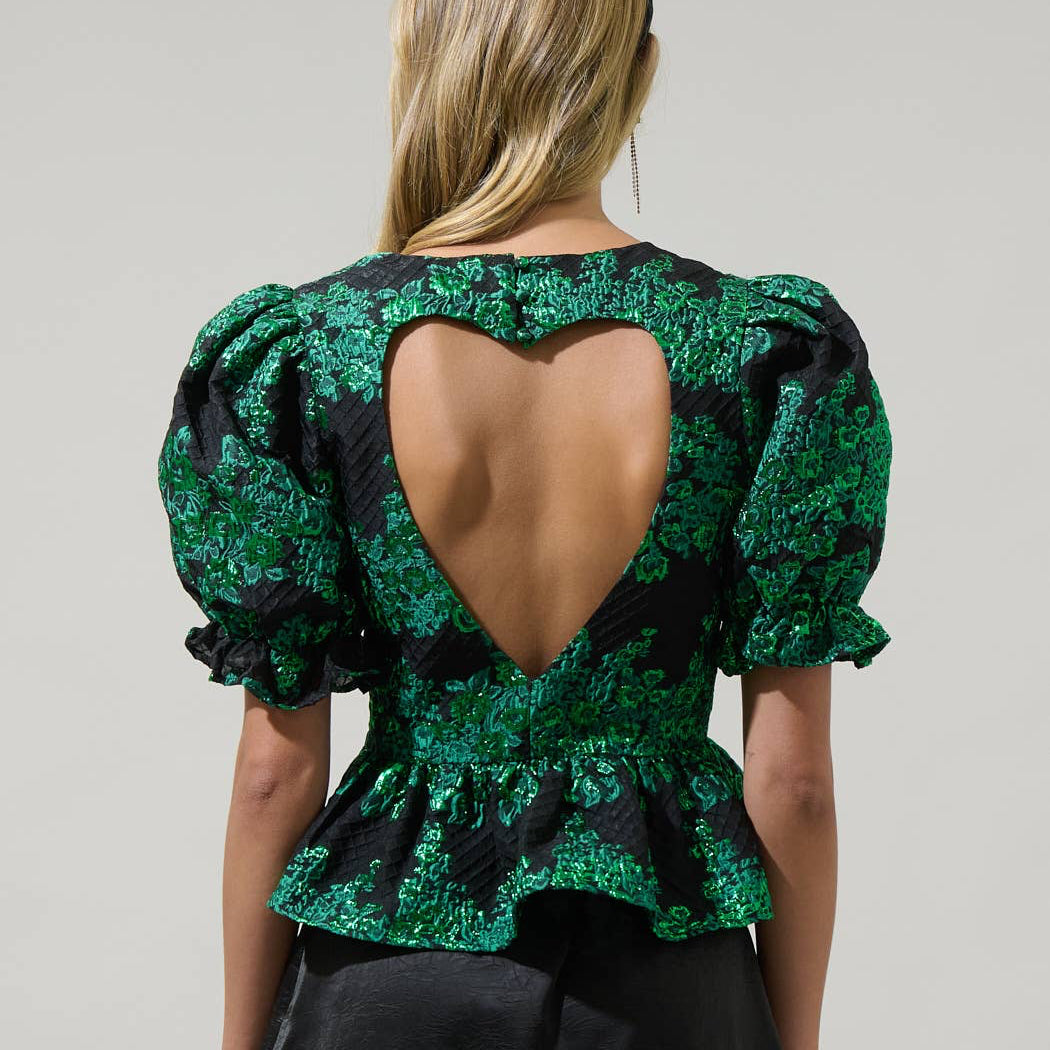 Whatever your plans may be, keep it cute when you wear the Elyna Jacquard Alena Cut Out Blouse. Short puff sleeves with elastic cuffs frame a round neckline that leads to a cute out heart shape in the back. It has a peplum touch at the end. Wear it with a skirt or pants to create a lovely look.

Details:

Puff sleeve
Heart cut out Peplum
Zipper
Color: Green/Black
Model is 5'9"" and wearing size XS
Measurements taken from size S - Chest: 17 1/2"" - Length: 22 1/4""