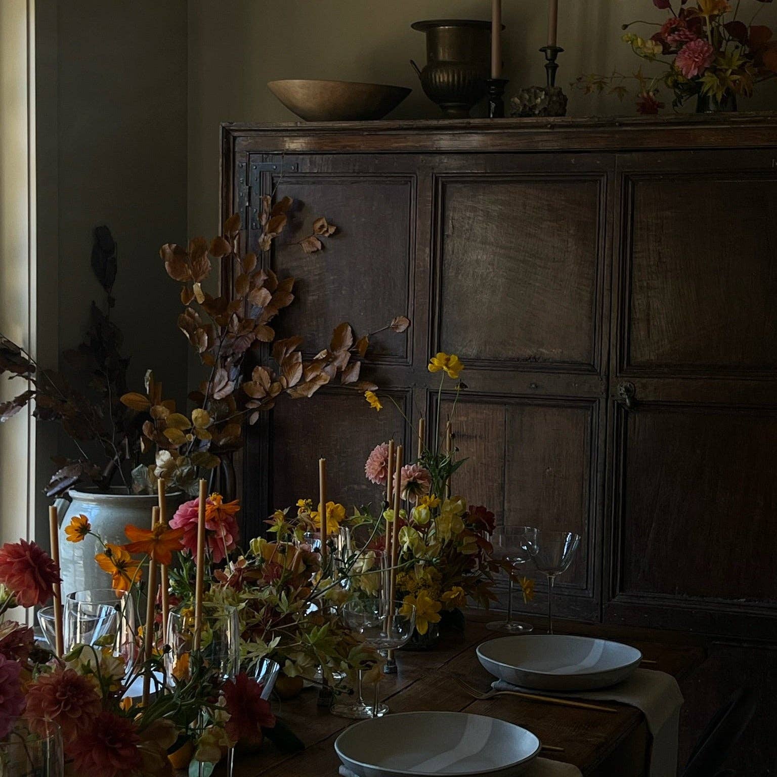Dining table with floral arrangements and a wooden cabinet in the background