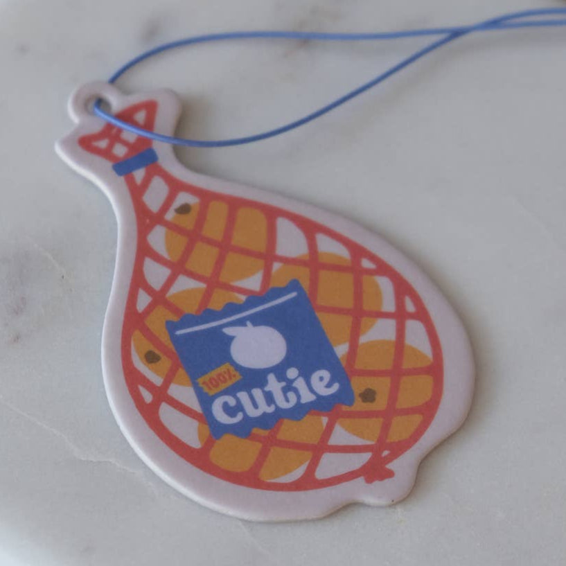 Air freshener shaped like a pineapple with 'cutie' text on a marble surface
