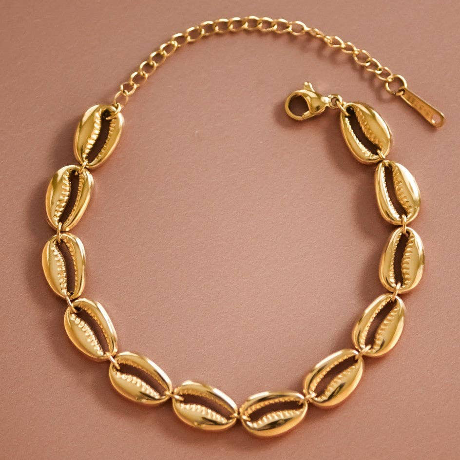 Elevate your beach-inspired jewelry collection with this stunning 18K gold plated stainless steel cowrie shell bracelet. Crafted from hypoallergenic materials, this piece is perfect for sensitive skin and designed to withstand daily wear with its waterproof and tarnish-resistant properties. The chunky chain design pairs beautifully with the natural cowrie shell shapes, making it an ideal summer accessory. To maintain its lustrous finish, avoid prolonged contact with lotions, perfumes, and cleaning products.