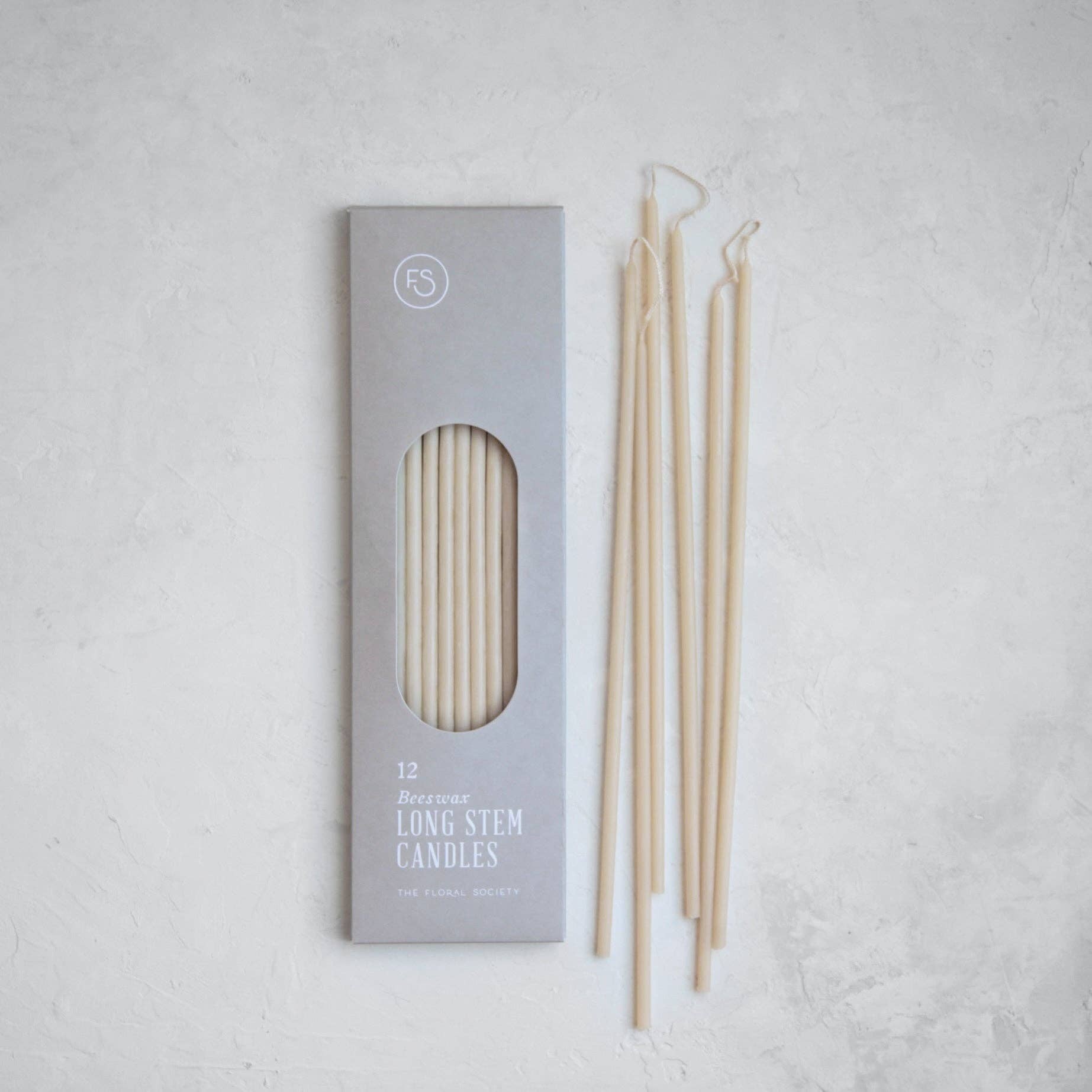 Set of long stem candles with packaging on a light gray background