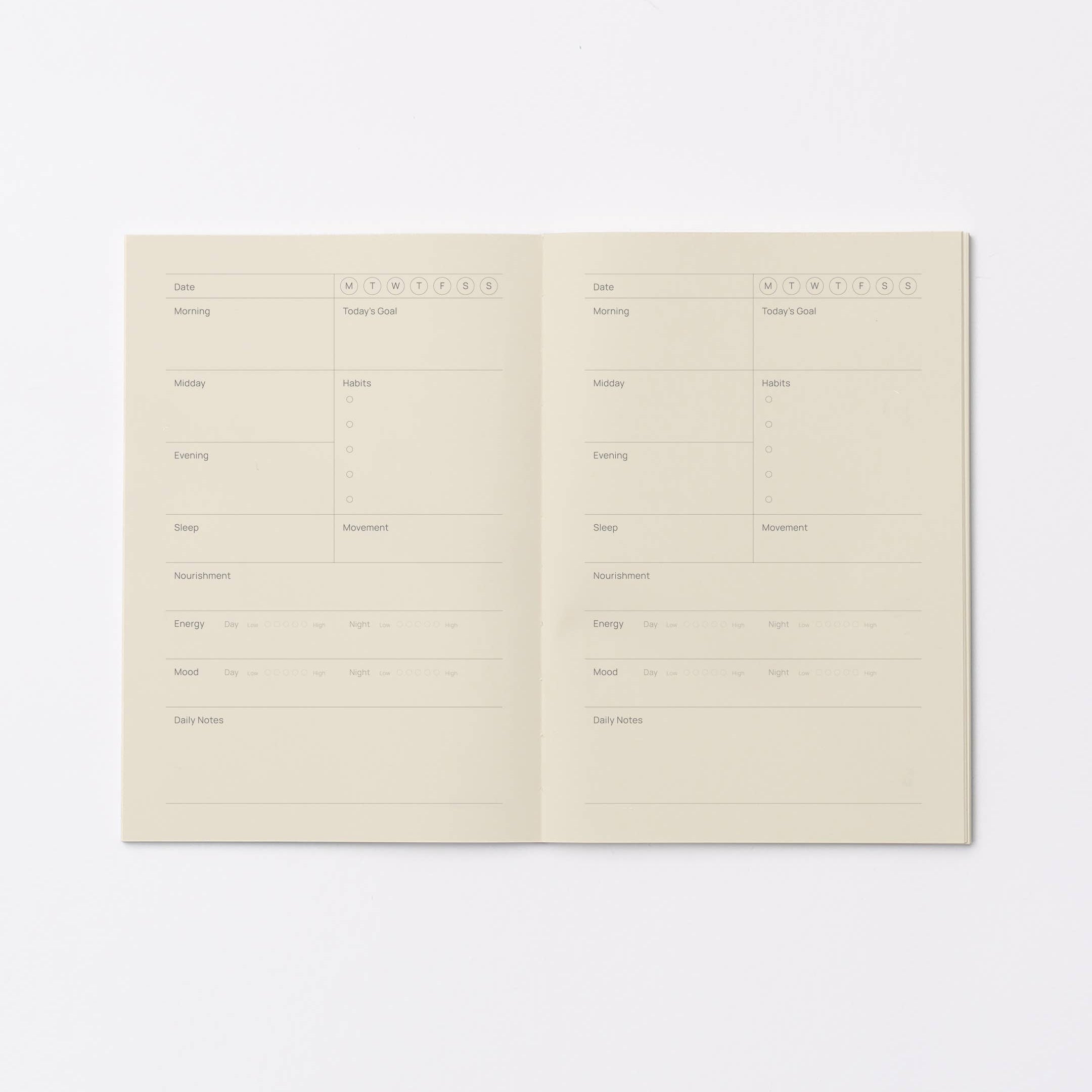 An open daily planner or journal spread on a clean white background, showing two cream-colored pages with printed daily planning fields and checkboxes.