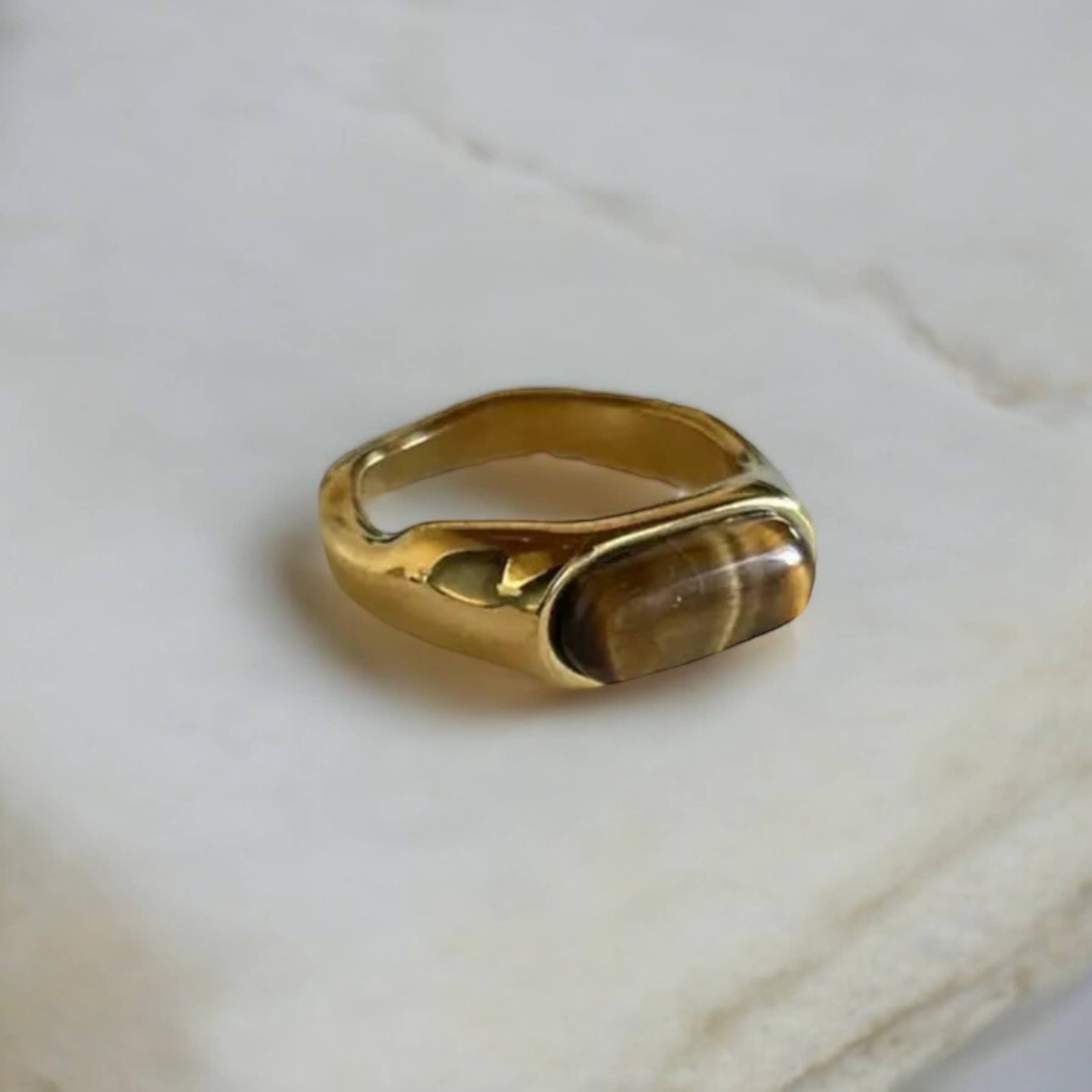 Gold ring with a stone on a marble surface