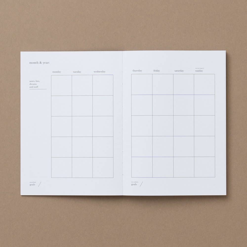 An open planner or notebook showing two interior calendar pages with columns for days of the week, photographed from above on a plain brown background.