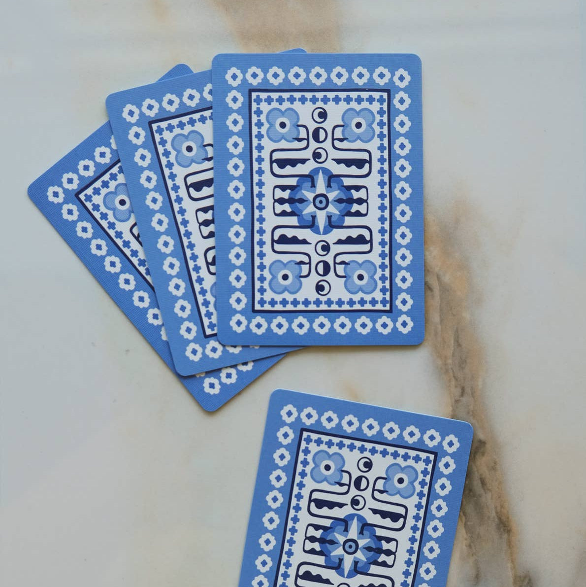 Blue playing cards with intricate designs on a marble surface