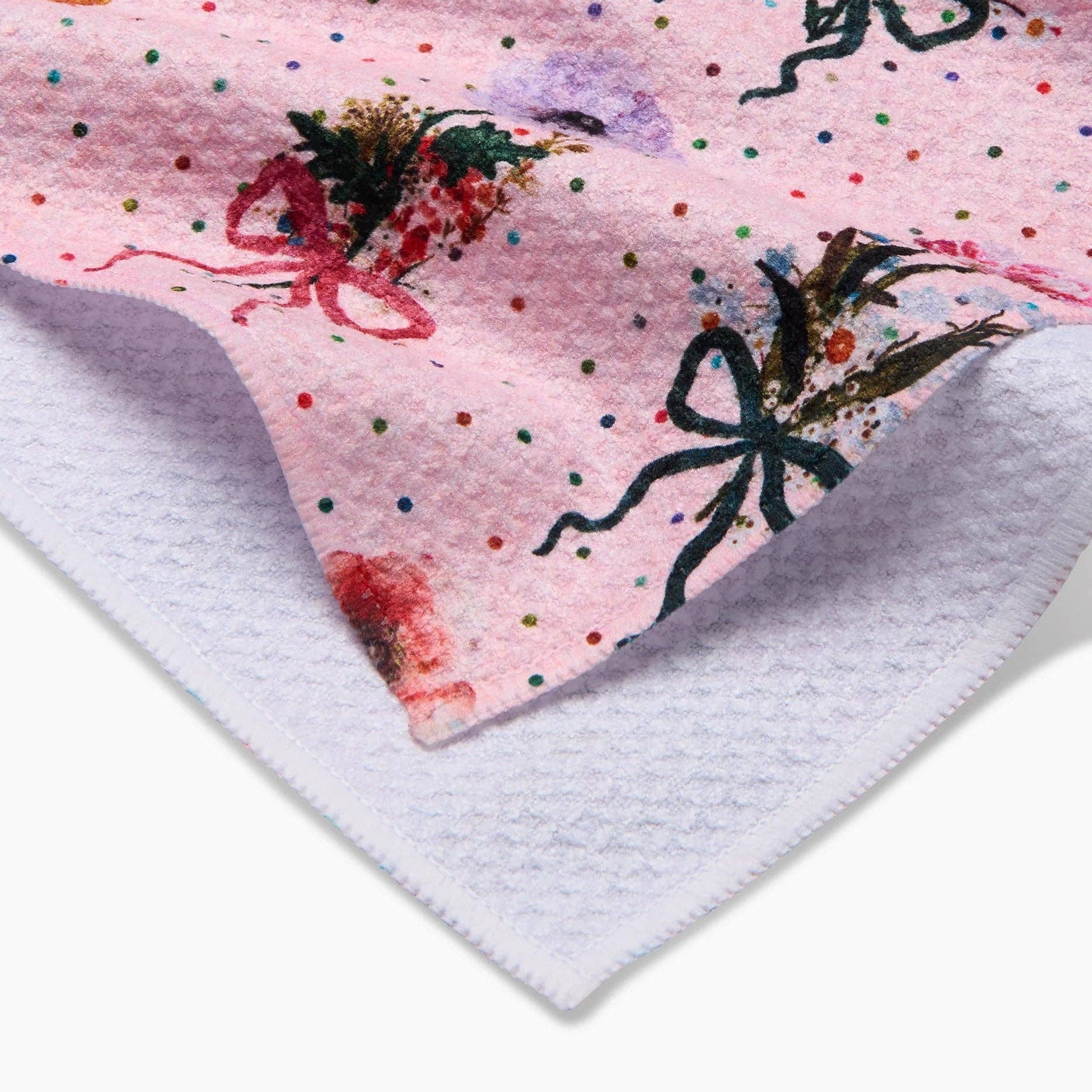 Close-up of a pink fabric with floral and bow designs on a white background Tea Towel