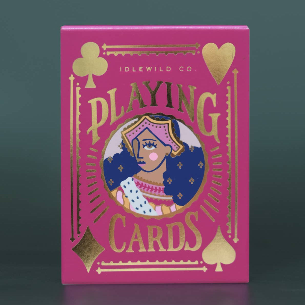Pink playing card box with gold accents and a central illustration on a dark gray background