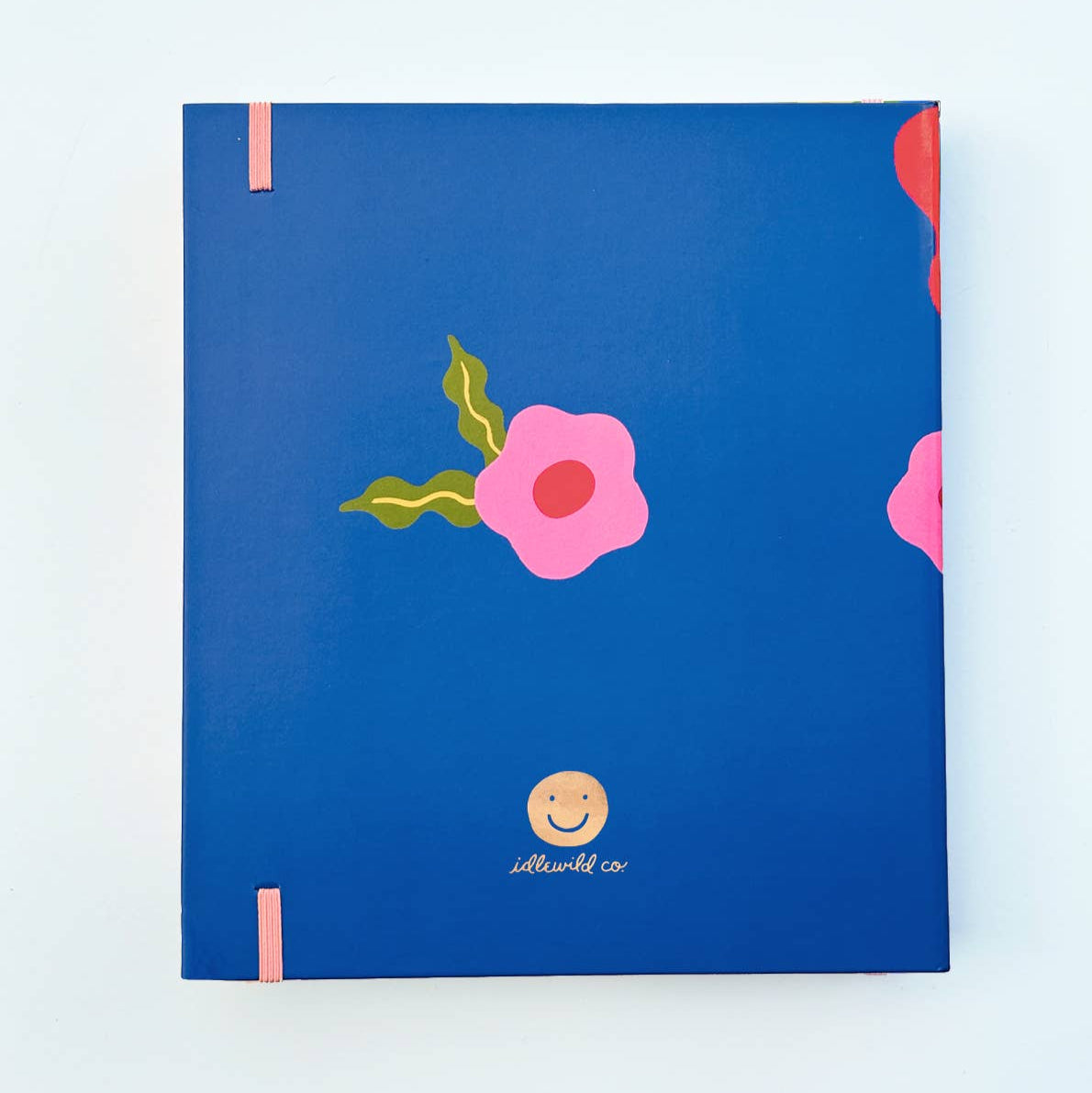 Blue notebook with pink floral design and a smiley face on a light blue background