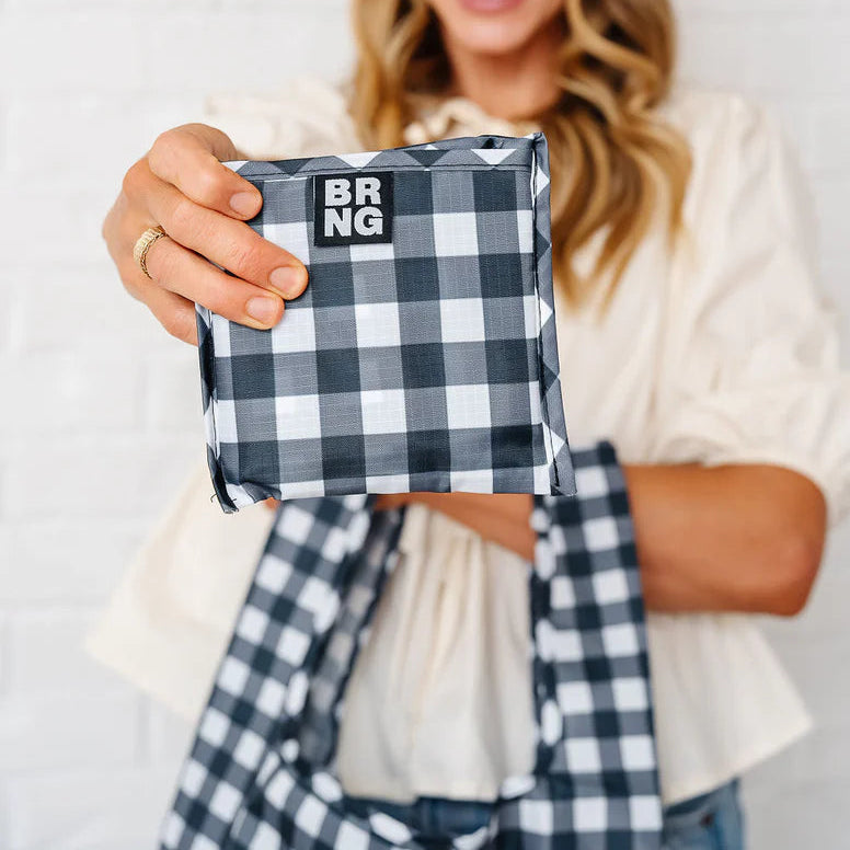 woman holding folded up gingham bag that has logo BRNG on the front