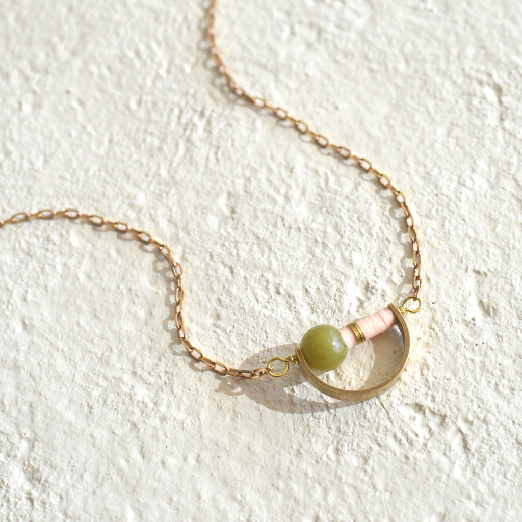 Round bead with color heishi beads in a brass crescent pendant.