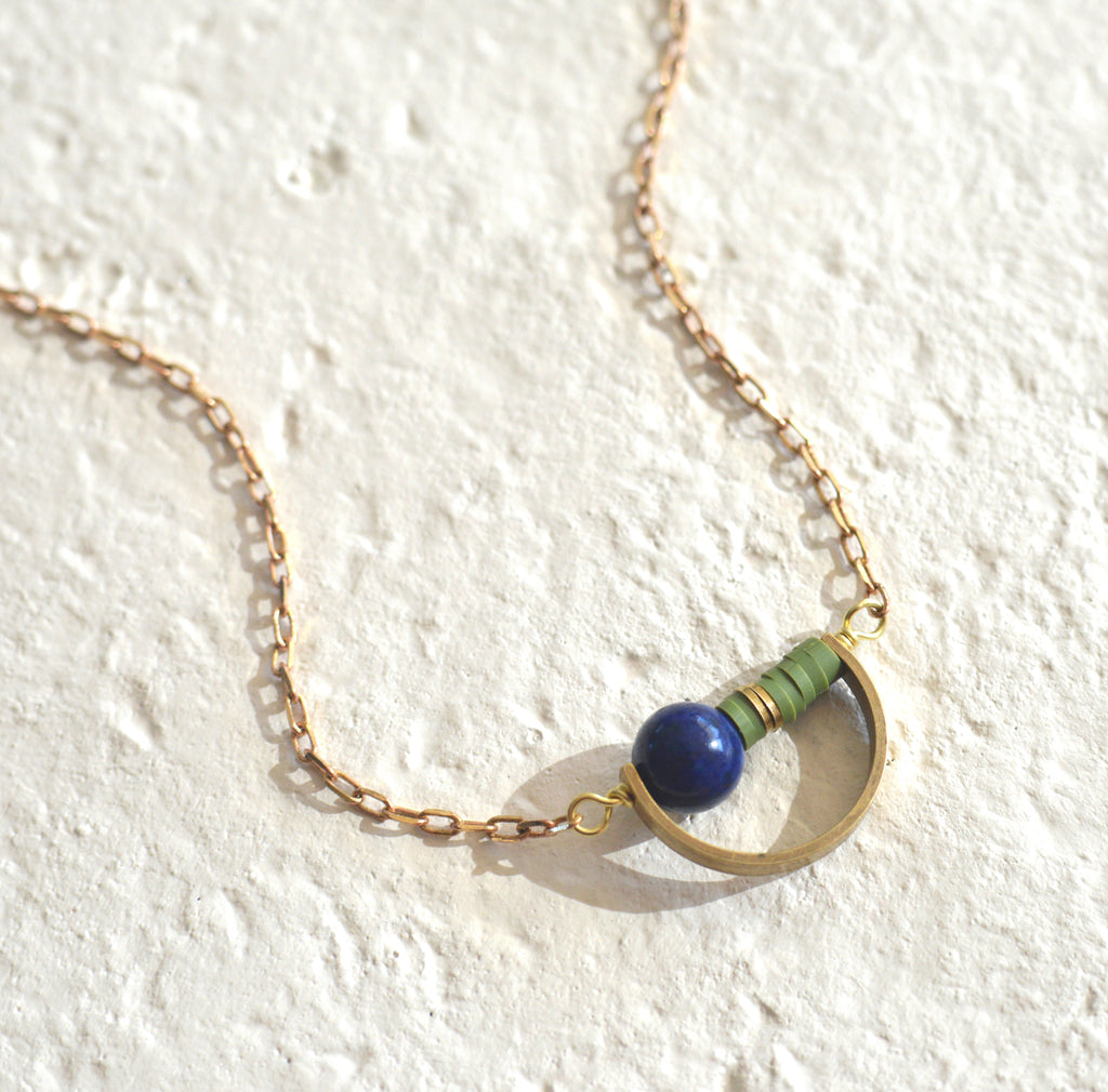 Round bead with color heishi beads in a brass crescent pendant.