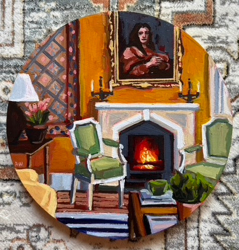 A living room with a fire burning in the fireplace adorned with an intricate white mantle. Two green chairs face each other and a coffee table is in view with a green plant and green coffee mug. The wall is painted a light orange and a portrait of a woman hangs above the mantle. 