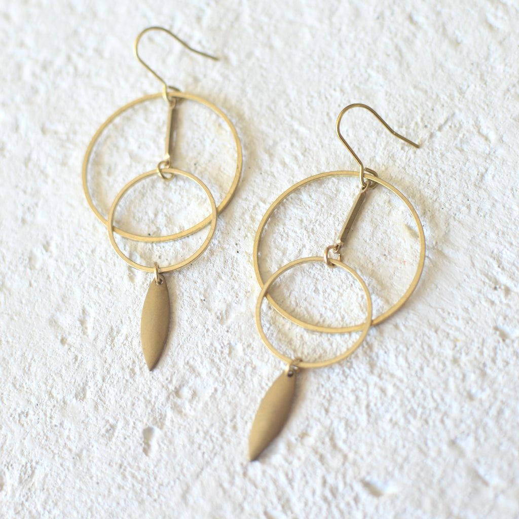 A perfect blend of chic and sleek, these light weight earrings feature cascading raw brass hoops with a drop charm detail. Ear wires are raw brass and hang 3" from top of hook. Nickel and lead free.