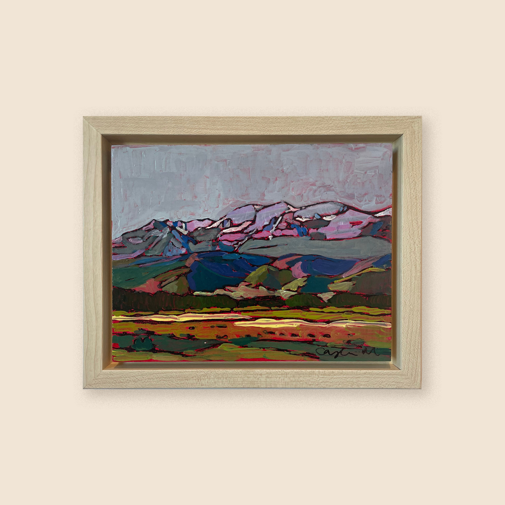 A distant view of the mountain scape with bright blues, pinks, oranges, and greens. There are rolling hills in front of the grandeur mountain range. 