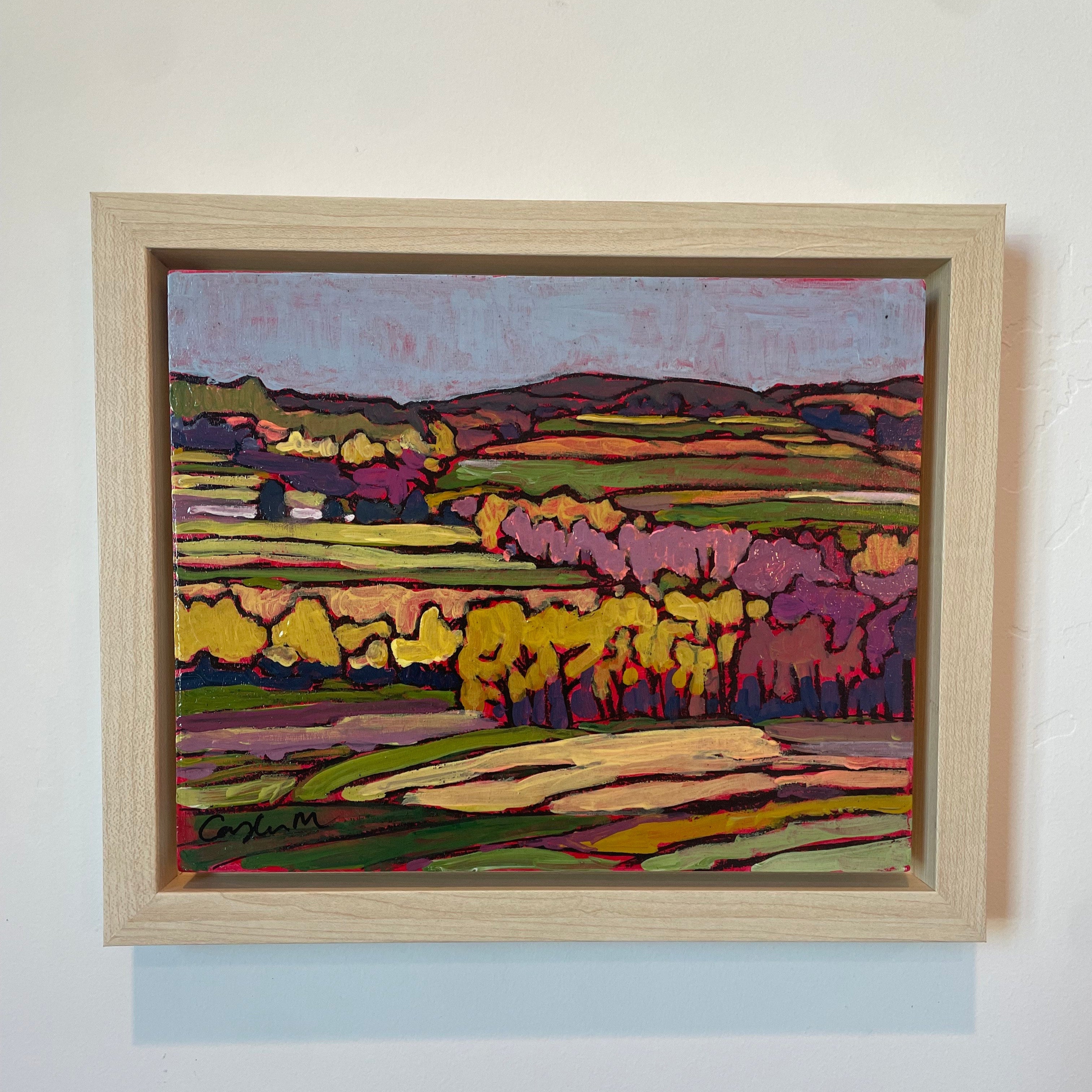 Rolling fields with trees interspersed at dusk. Bright hues of orange, yellow, pink, and purple are used to show the evening light. The sky is blue and purple. 