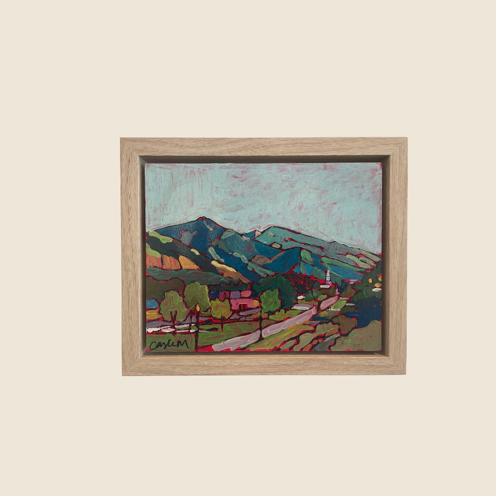 Landcape mixed media painting, with green blue mountains, winding road through the foreground of trees and grass, leading to a town nestled at the foothills of the mountains